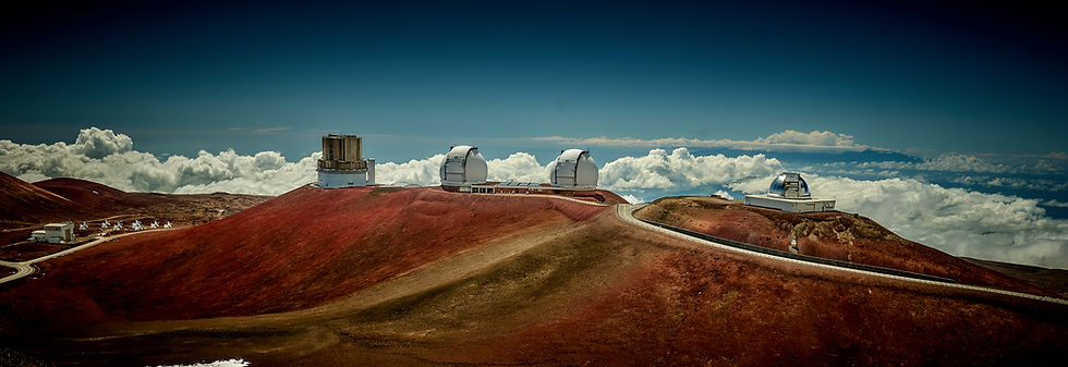 Four major telescopes on the Mauna Kea volcano summit on a clear sunny day with blue sky