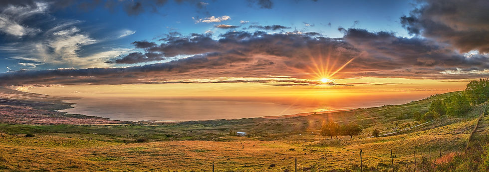 A bright red and orange sunset stretches across the whole South Kohala Coast as seen from high up on the Kohala Volcano