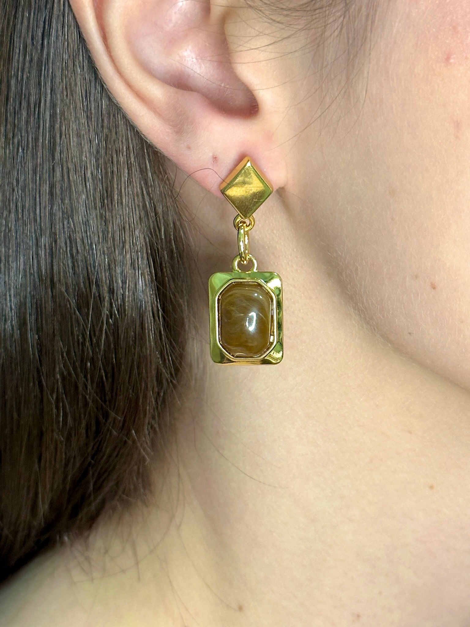 Brincos em metal dourado, couro estonado e resina