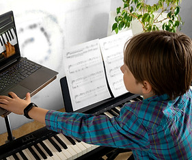 Boy learning to play the piano in distance learning via laptop over the Internet.jpg