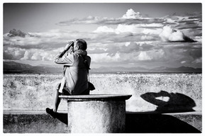 Black and white photo of a man looking through binoculars at the distance by Mallorca based artist Martin de la Foi