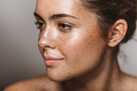 Smiling woman with freckles, radiant skin, Skin Leaf Cosmetics, natural beauty.
