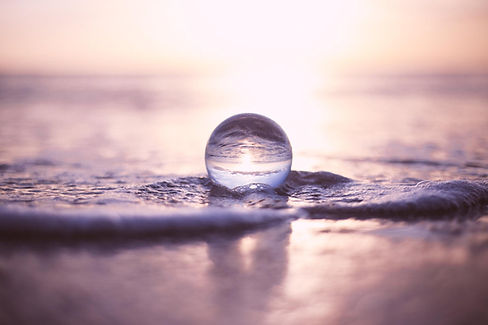 Boule de cristal sur sable mouillé plage avec reflets océan et lumière douce symbolisant clarté sérénité et énergie retrouvée en hypnose bioénergie quantique kinésiologie à Mulhouse Pulversheim