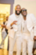 Two smiling men in white suits at an event