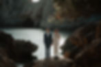 Bride and groom holding hands and posing editorially on rocks in a stunning ocean bay during their adventurous elopement in Mallorca, Spain.