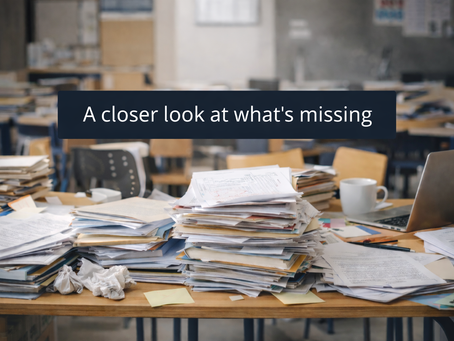 A cluttered teacher’s desk covered in paperwork and marking, illustrating workload pressure, stress, burnout  and the impact of job design on staff wellbeing in school
