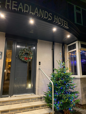 Festive entrance of The Headlands Hotel at night with wreath, Christmas tree, and seasonal lights welcoming guests to the festive weekend in Scarborough