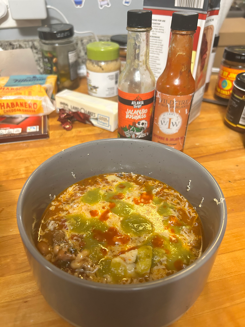 Bowl of super secret spicy chili with cheese and hot sauces- 'Atlanta Burns' and 'Wildfire in Wonderland'