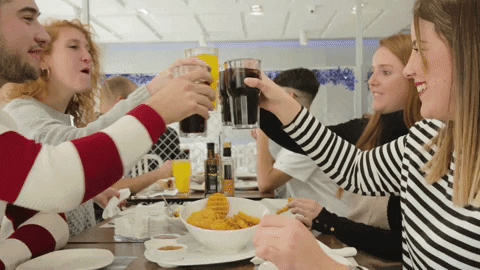 Guests celebrating with drinks at a table with food.