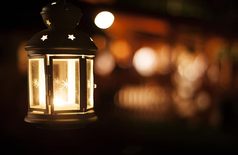Decorative metal lantern lit by a glowing candle in night