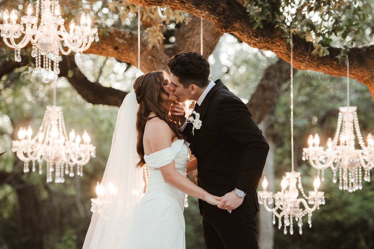 Outdoor ceremony beneath a chandelier-lit oak tree at The Addison Grove wedding venue in Central Texas.