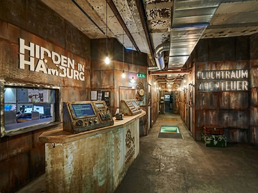 Empfangsbereich des Escape Rooms Hidden in Hamburg – industrielles Steampunk-Design mit Rostoptik, Schalttafel und Schild „Fluchtraum Abenteuer"