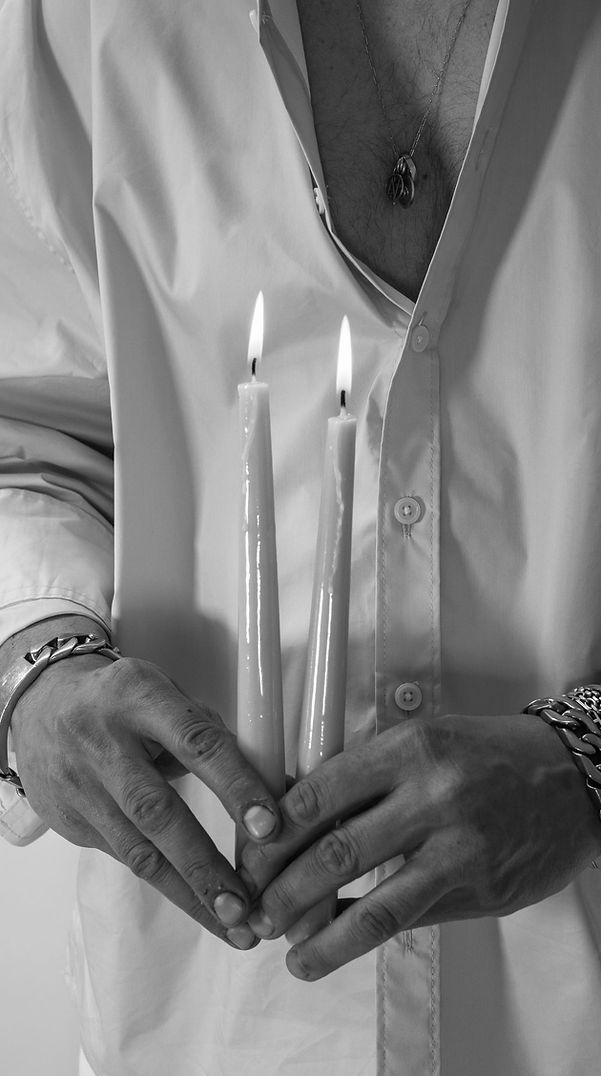 Manos del artista sosteniendo dos velas encendidas, en una imagen en blanco y negro tomada en el taller de cerámica Abenval.