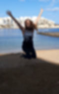 Our team member Jen at the beach. She is jumping and smiling.