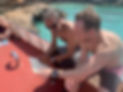 Two people looking at a chart, both of them sitting on a boat in the sunshine.