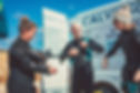 Three divers getting ready for a dive. All three are talking with each other and are smiling. In the background is one of our diving vans.