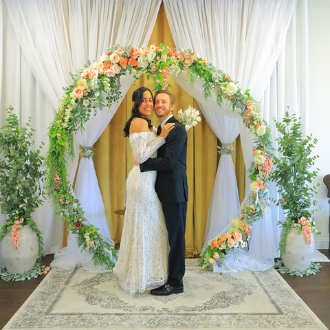 A smiling newlywed couple celebrate exchanging their vows at the altar in a simple intimate wedding setup. 