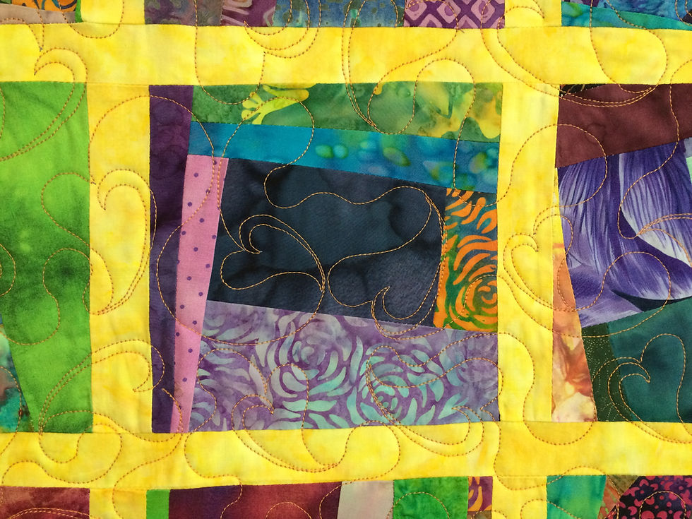 closeup of scrappy blocks with floating hearts quilting design