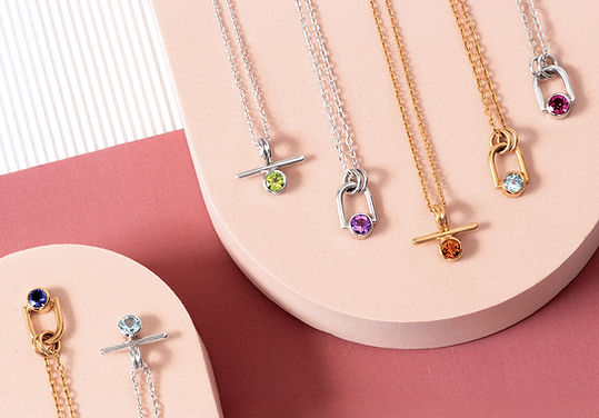 silver and gold gemstone necklaces display on pink background, by Heather O'Connor