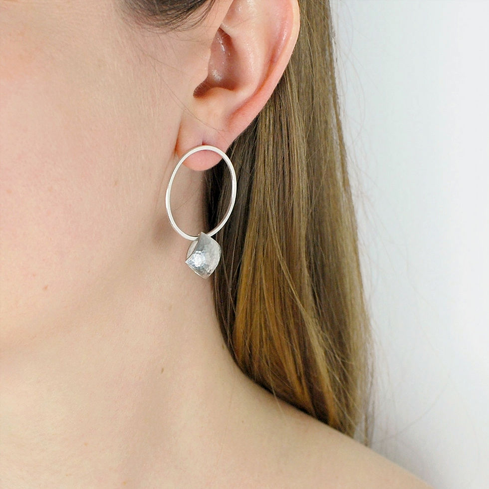 Silver textured pillows hung on slim silver hoops, earrings shown worn on ear