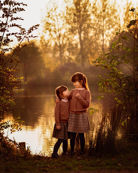 Herfstige gezinsshoot van twee kinderen aan het water, vastgelegd tijdens golden hour door fotograaf Vicky Spaenhoven.