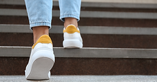 A person's shoes on stairs, with right shoe a step above the left shoe.