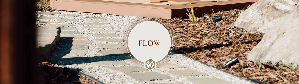 Stone path and mulch landscape with rocks and plants. A circular sign reads "FLOW" in the center. Calm and earthy atmosphere.