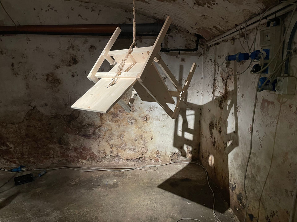 Installation by Antonio Scarponi: innocent chair suspended with a rope projecting shadows on the floor and wall