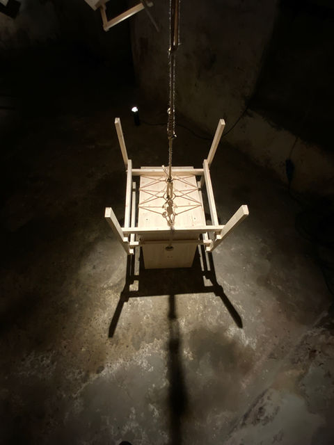 Installation by Antonio Scarponi: innocent chair suspended with a rope projecting shadows on the floor