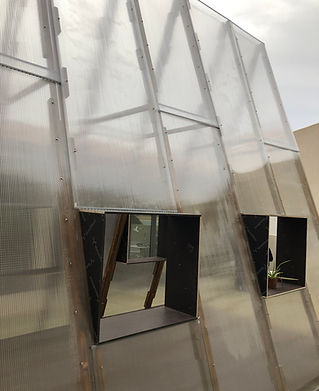 Udategia is a Basque word meaning the place where summer is produced and kept. The pavilion translates this idea into a temporary architectural structure capable of hosting growth, care, and collective engagement.
Built in December 2020 in a limited timeframe, the pavilion was assembled on site with simple means and lightweight materials. The structure was conceived as a compact greenhouse, designed to operate autonomously while remaining open to public interaction. Through controlled environmental conditions, the pavilion supports the cultivation of food and herbs, extending the notion of seasonal production beyond its usual temporal boundaries.
The architectural system is based on a lightweight timber frame covered with polypropylene panels, providing protection from wind and saline air while allowing light and heat to accumulate. The pavilion’s proportions and construction logic enable rapid assembly, disassembly, and adaptation to different contexts.
Installed on the terrace of the Institute for Basque Architecture in the historic center of San Sebastian and facing the bay of La Concha, the pavilion functions as both an infrastructural and social device. The cultivated produce becomes part of small public events, transforming the pavilion into a temporary interface between architecture, food production, and collective use.
Mediate designates the transfer of knowledge through cultivation practices, environmental control, and collective care.
Activate refers to the pavilion’s capacity to generate use, production, and social interaction within a temporary architectural framework.
