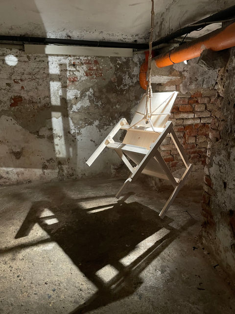 Installation by Antonio Scarponi: innocent chair suspended with a rope projecting shadows on the floor and walls