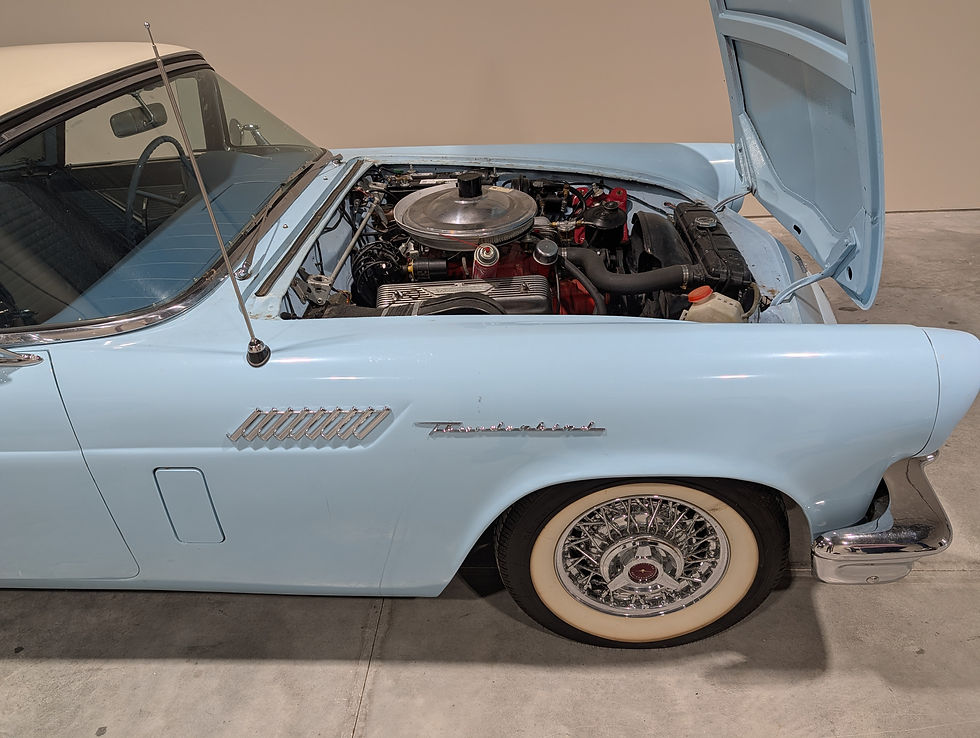 Dusty Blue TBird with the hood open inside an auto repair shop