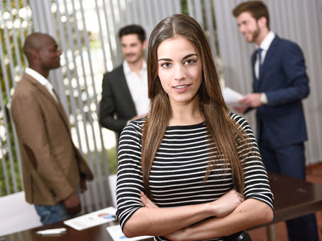 Two people in an office discussing a document on a tablet. Both wear glasses and business attire. The mood is focused and serious.
