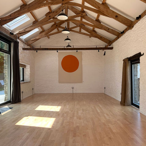 Bright yoga studio with wooden floor and large orange circle art Horizon Yoga