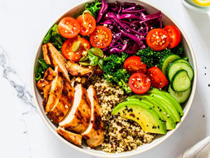 High protein salad with grilled chicken, quinoa, chickpeas, greens, and toppings in a bowl