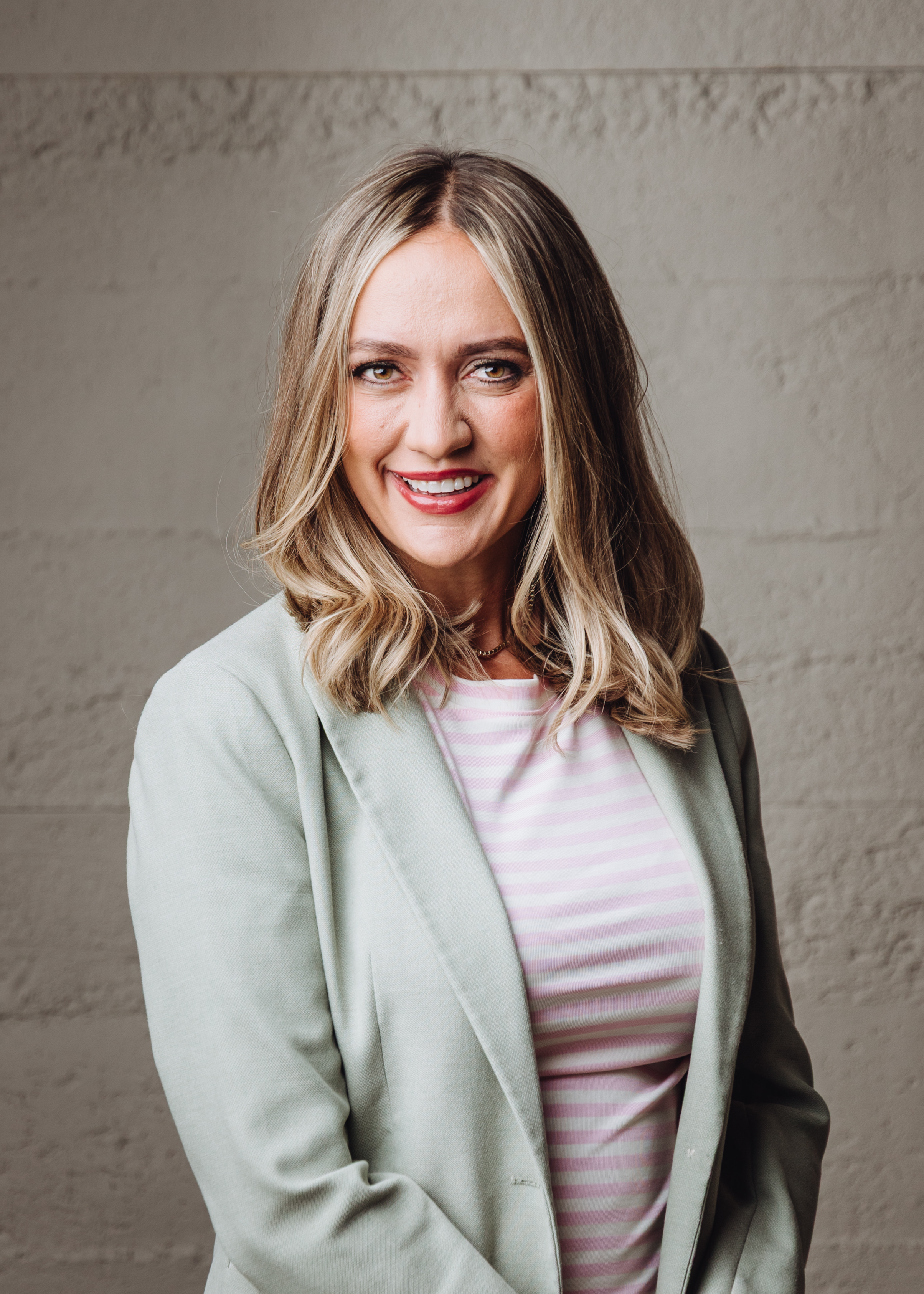 Mel, smiling, in a sage blazer