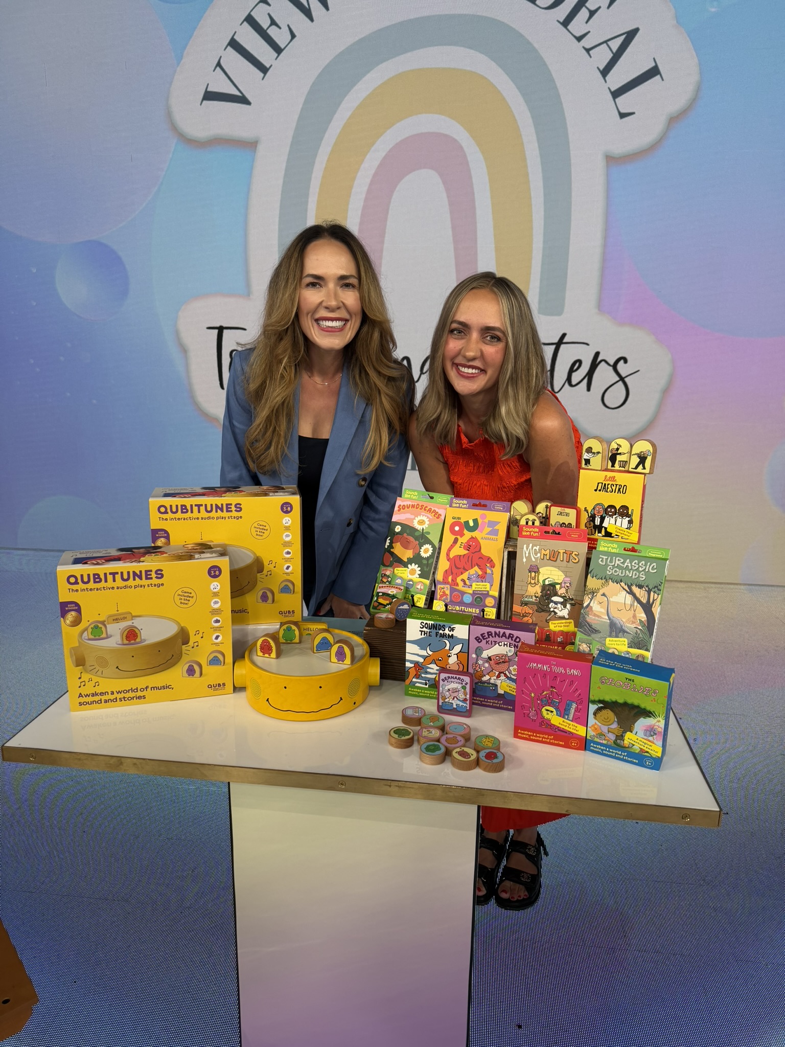 Mandy and Mel behind a table of toys on the set of The View