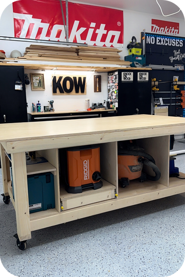 The Knock On Wood workshop featuring a work table, tool boxes, Makita banner, miscellaneous tools and a KOW sign.