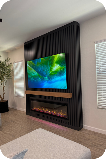Black slat wall with a stained wood mantel over an electric fireplace. 