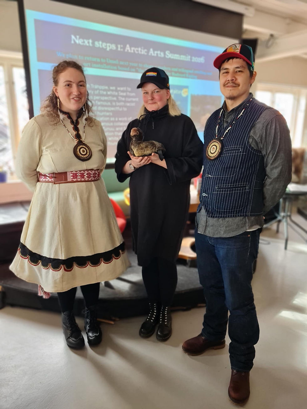 Kim Rehnman, Såhkie's board member, center, holds a seal figurine, made by artist Garrett Paul Pletnikoff (right) with companion Hannah Zimmerman (left), both from Alaska.