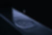 Plano detalle dinámico de una gota de agua callendo sobre una franja de agua en medio de la oscuridad. Imagen Expresiva en escala de grises con tintes violetas sutiles