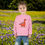 Thumbnail: Young girl wearing pink dinosaur shirt, smiles in a flowery field. My Site 1