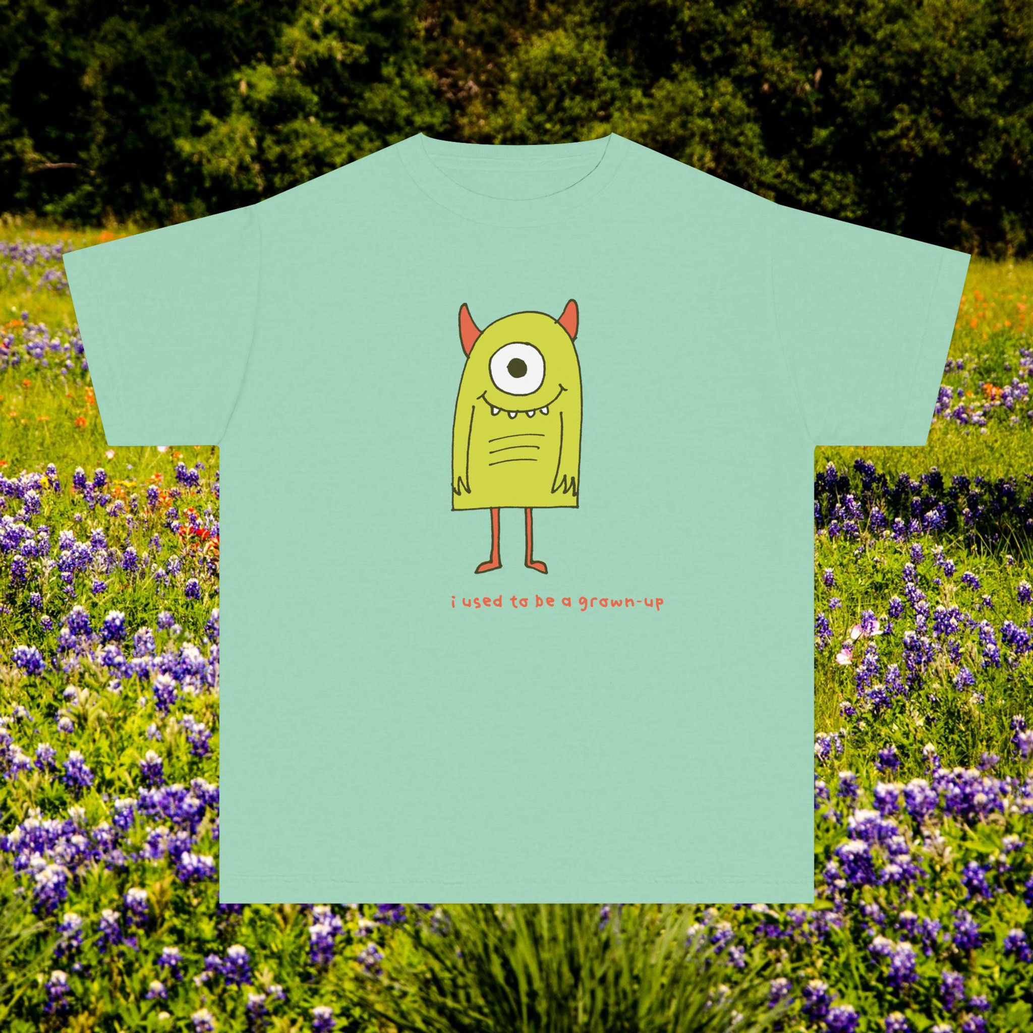 Green t-shirt with a friendly monster cartoon and text