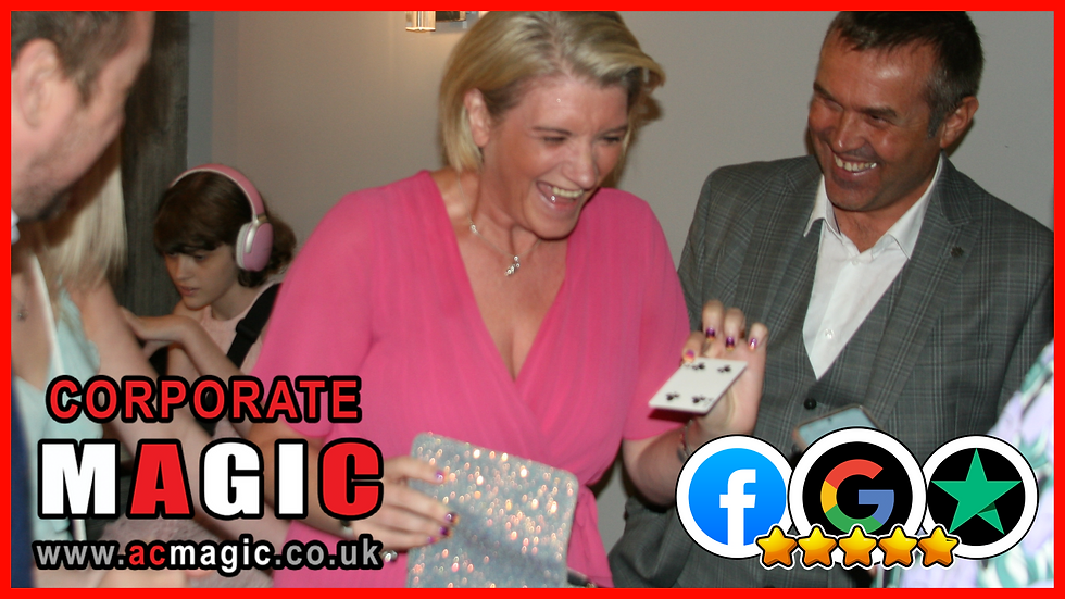 A woman in pink laughs holding a playing card, while a man smiles beside her. A child with headphones is in the background. Text: Corporate Magic, www.acmagic.co.uk.