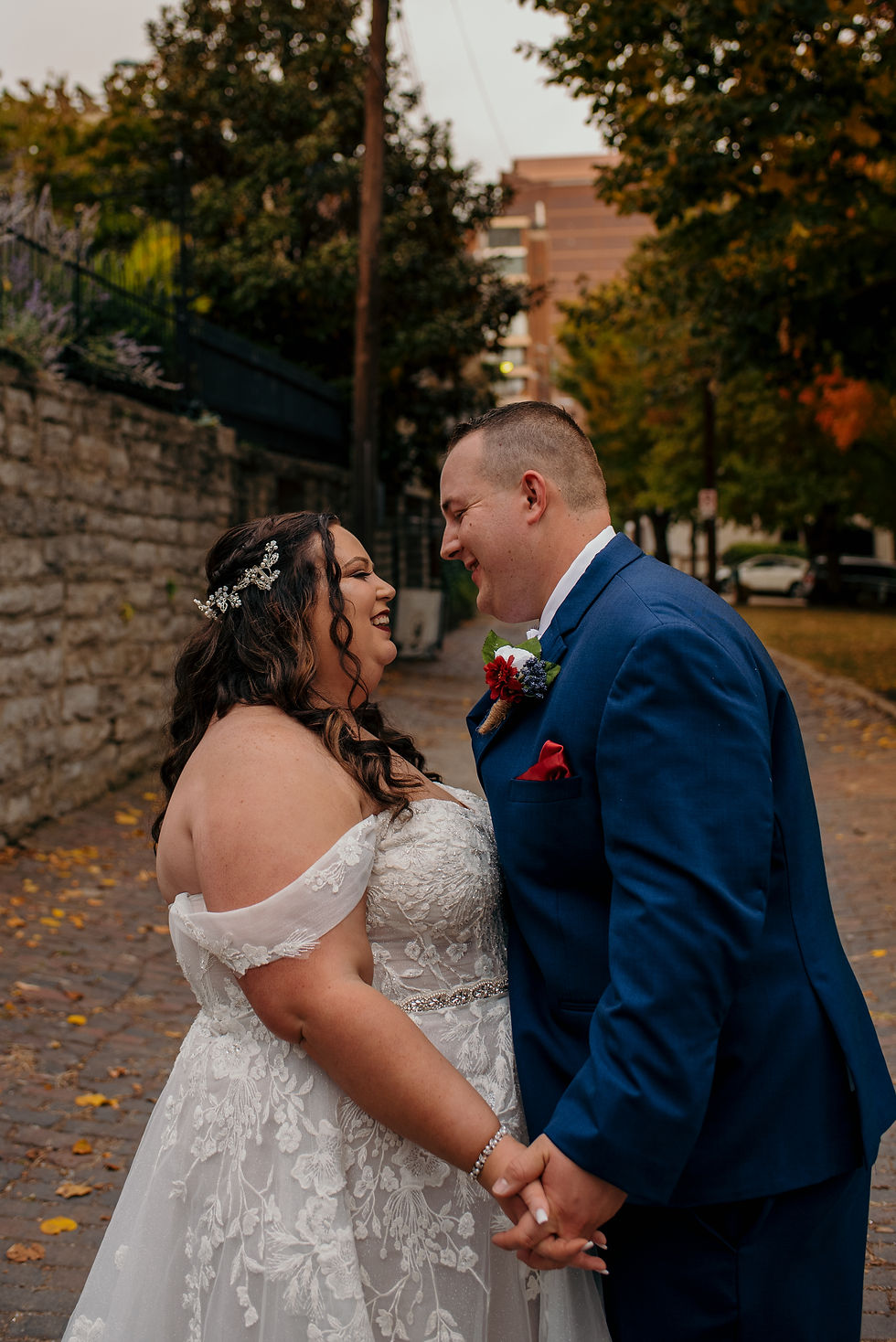 Plus sized bride and groom hold hands and face one another on their wedding day at George Rogers Clark Park in Covington, Kentucky on October wedding day.
