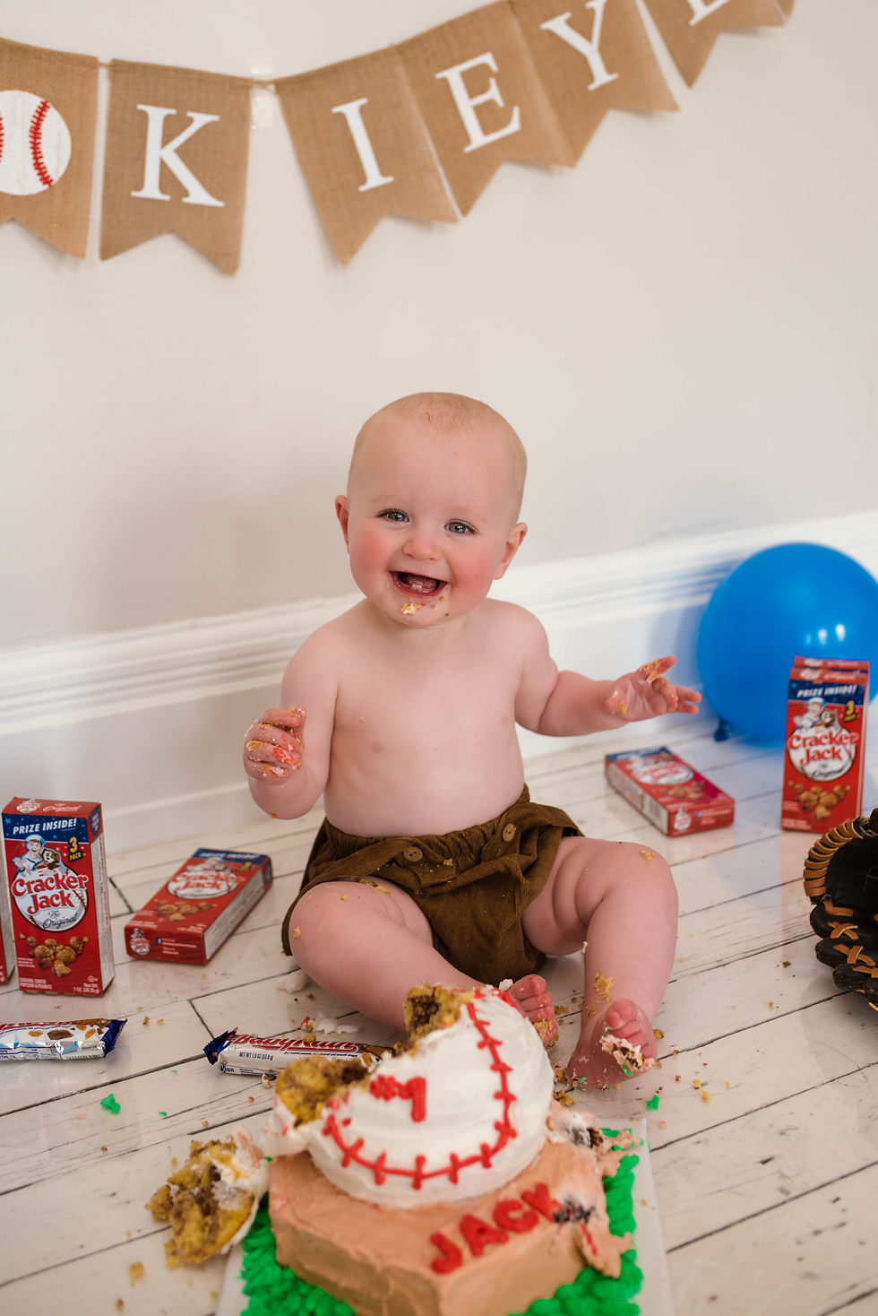 One year old boy sits and eats cake for "My Rookie Year" baseball first birthday cake smash photoshoot in Cincinnati, Ohio.