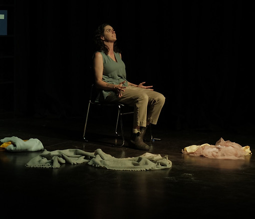 A woman sits on a chair looking up to the sky with clothes around her.