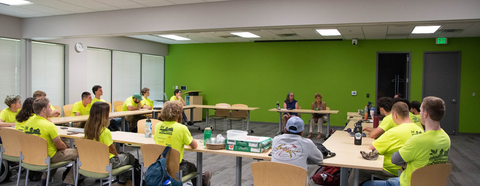 Crew members sitting at tables facing the speaker