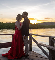 Novios posando frente a un muelle en el atardecer