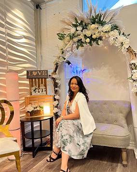wedding decorations and background, wedding venue and decor, hosted by leen sitting on couch for a wedding emceeing event. Wearing long dress and white blazer, posing before hosting an event.